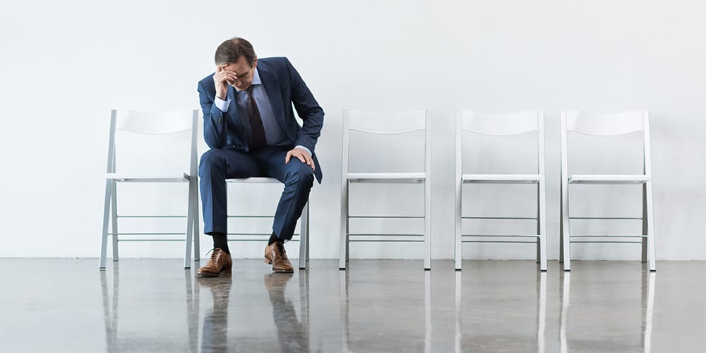 Photo of a professionally dressed man looking displeased after making one of the worst mistakes that lawyers can make during arbitration.