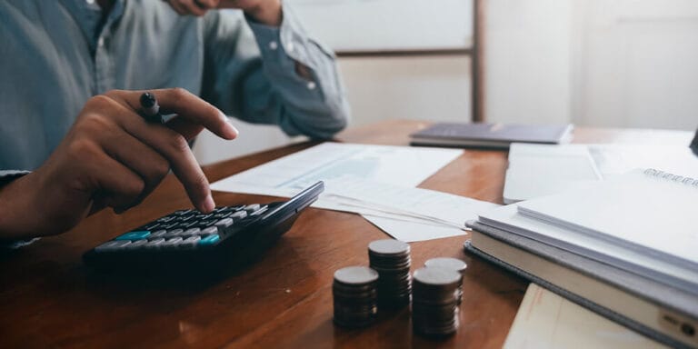 Photo of an attorney using a calculator and spreadsheets to determine the costs of remote depositions