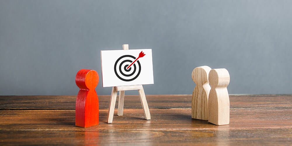 Concept art of wooden figures situated next to a red bullseye illustrates the kind of affordable targeted marketing law firms can use during the pandemic.