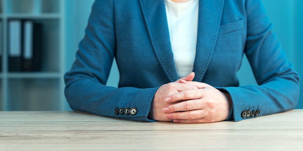 A professionally dressed female attorney displays good posture, which is an important part of deposition body language.